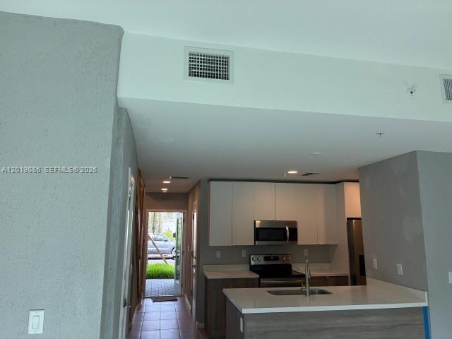 A modern kitchen features white upper cabinets, dark lower cabinets, and a stainless steel microwave — 2511 Pierce St # 6, Hollywood FL 33020, HOLLYWOOD, FL