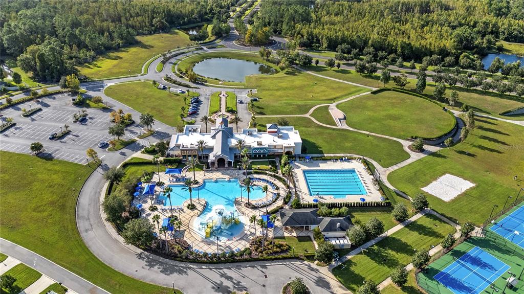 An aerial view shows a community clubhouse with a swimming pool, lap pool, and tennis courts — 9657 ASHWORTH PLACE, LAND O LAKES, FL