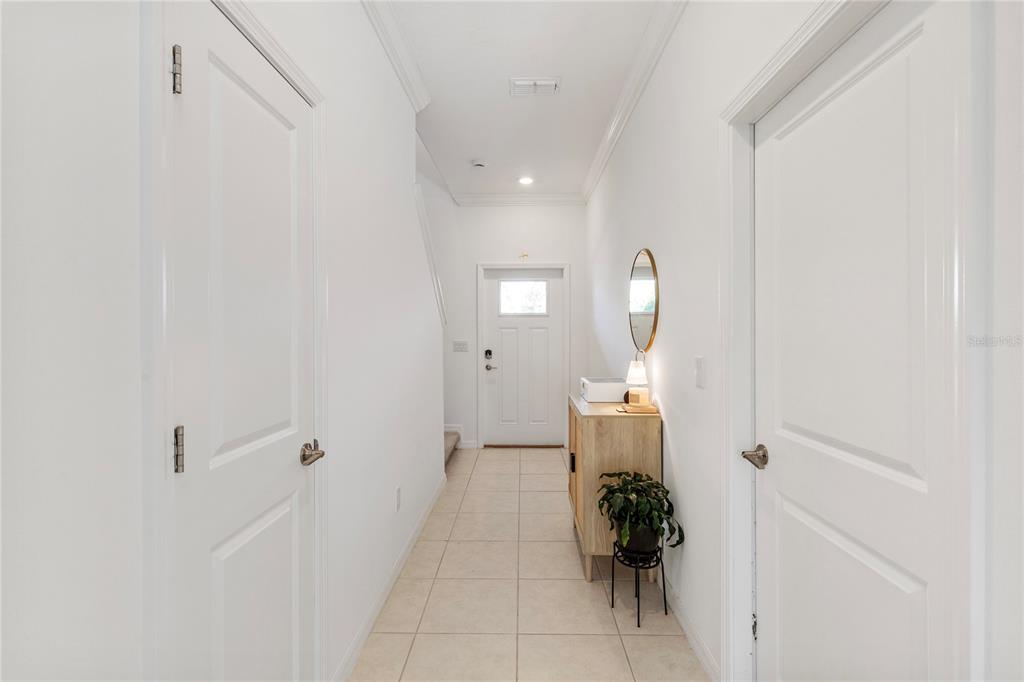 A bright entryway features white walls, tiled flooring, two closed doors, and a wooden console table — 9657 ASHWORTH PLACE, LAND O LAKES, FL