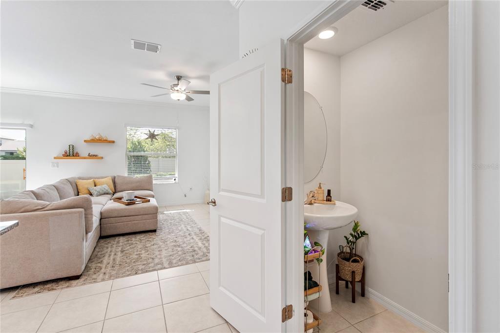 A view from a small powder room looking into a living room with a sectional — 9657 ASHWORTH PLACE, LAND O LAKES, FL