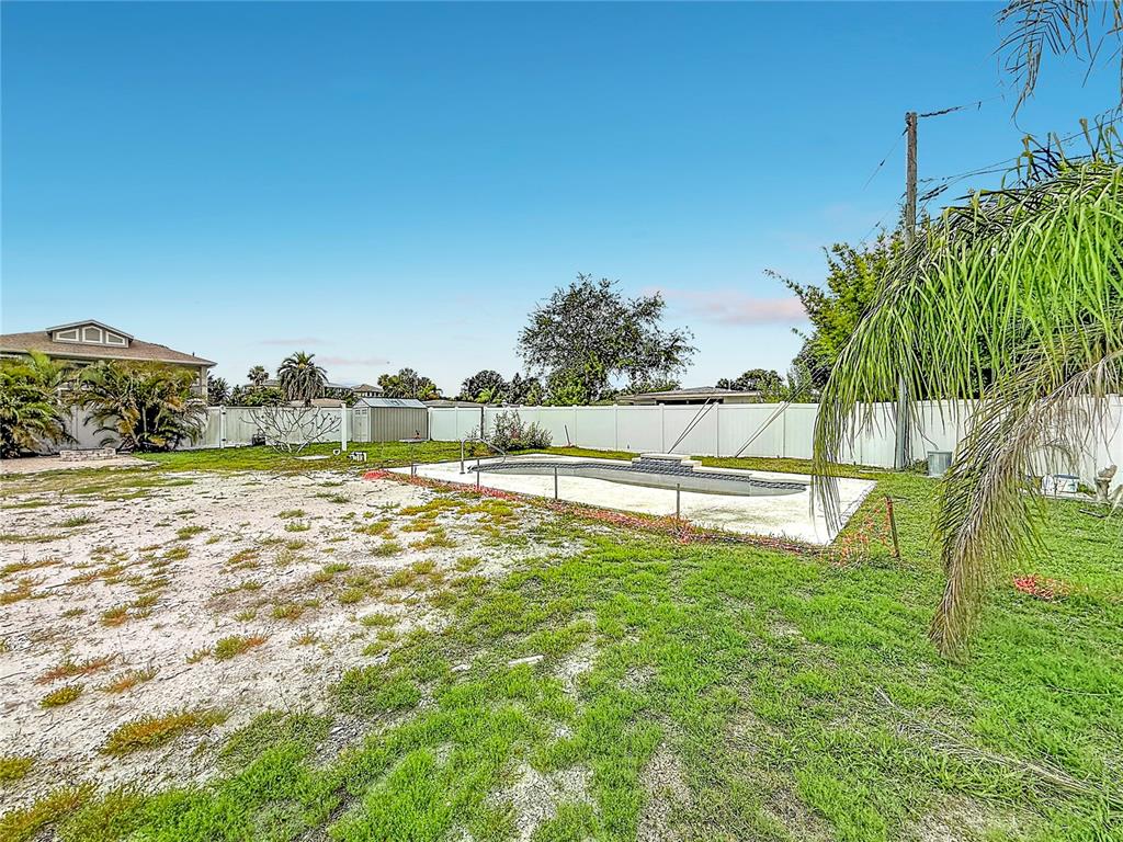 A backyard features a fenced-in swimming pool, a storage shed, and a large grassy area — 2464 DEL RIO WAY, DUNEDIN, FL