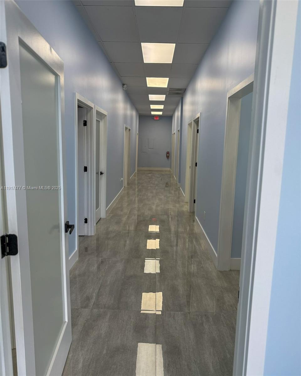 A long, narrow hallway features light blue walls, gray tile flooring, and recessed ceiling lights — 9447 SW 56th St # 49, Miami FL 33165, MIAMI, FL