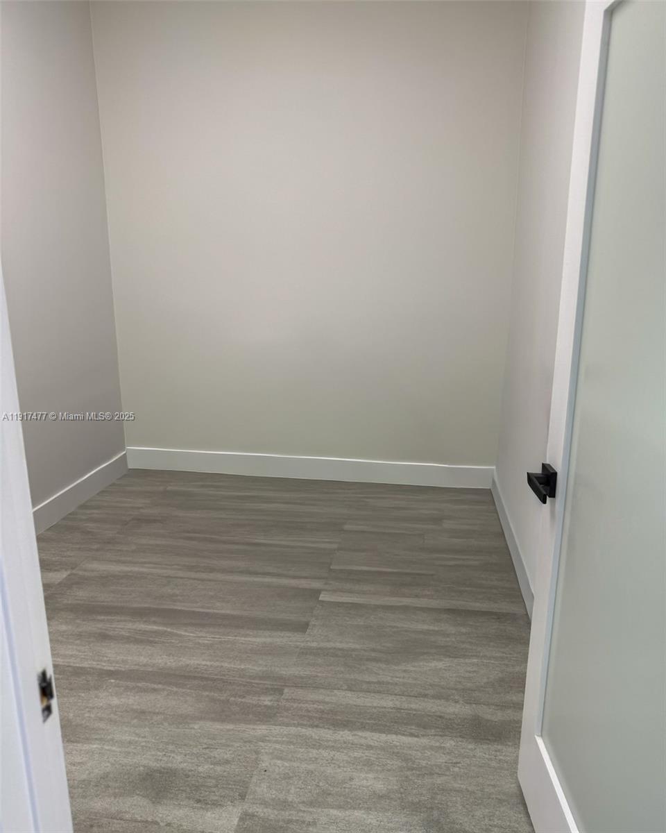 A small, empty room features light gray wood-look flooring, white walls, and a glass door — 9447 SW 56th St # 49, Miami FL 33165, MIAMI, FL