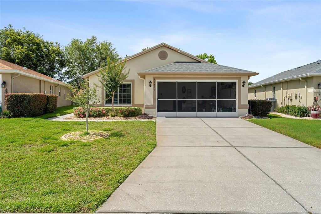 A single-story house with a beige stucco exterior, a screened garage, and a concrete driveway — 11422 INMAN COURT, SPRING HILL, FL