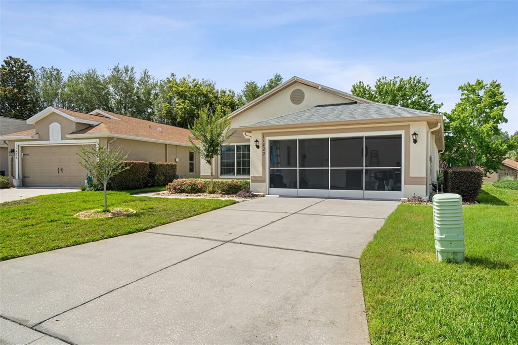 A single-story suburban house with a concrete driveway and a screened-in garage area — 11422 INMAN COURT, SPRING HILL, FL