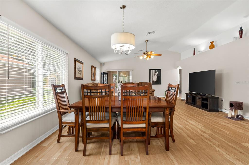 A dining area with a wooden table and chairs sits in an open-concept living space — 11422 INMAN COURT, SPRING HILL, FL