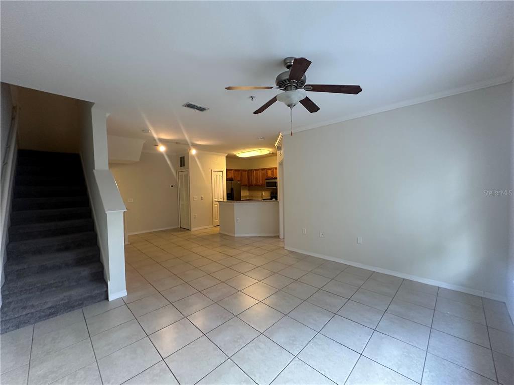 An open-concept living area features tile flooring, a staircase, and a kitchen with a breakfast bar — 6119 METROWEST BOULEVARD UNIT 103, ORLANDO, FL