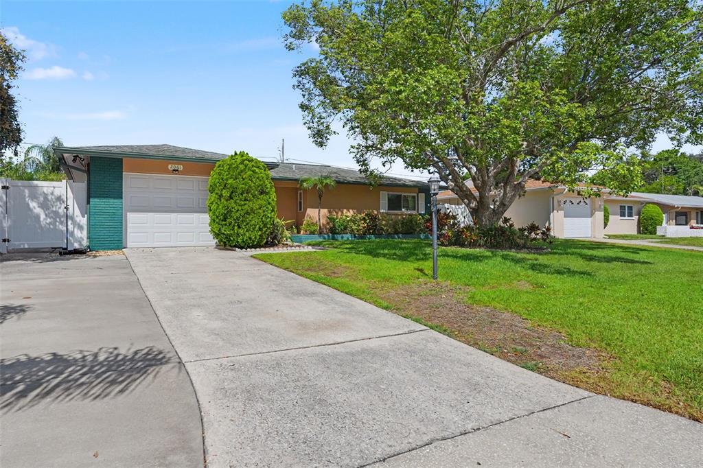 A single-story house with a concrete driveway, green brick accents, and a large shade tree — 2061 FAIR OAK DRIVE, CLEARWATER, FL