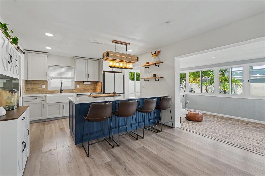 A kitchen features a blue island with bar stools, white cabinets, and wood-look flooring — 2061 FAIR OAK DRIVE, CLEARWATER, FL