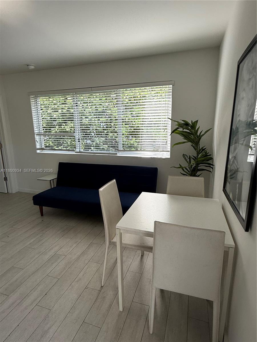 A dining area with a white table and chairs sits next to a blue sofa — 1601 Meridian Ave # 101, Miami Beach FL 33139, MIAMI BEACH, FL