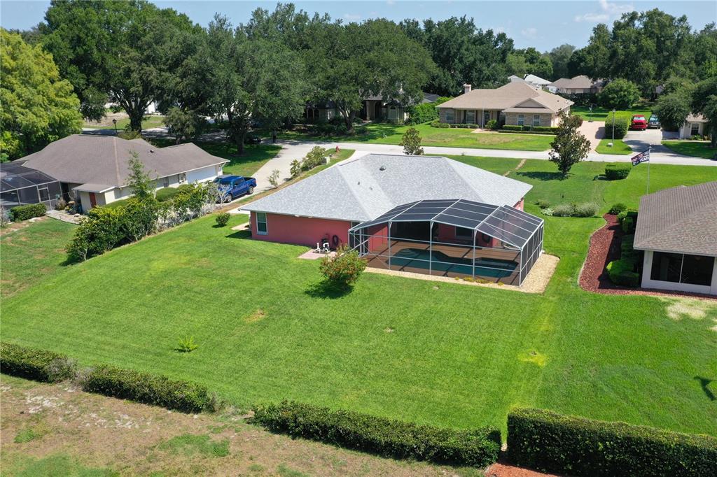 An aerial view of a pink house with a screened-in pool and a large backyard — 11208 HASKELL DRIVE, CLERMONT, FL