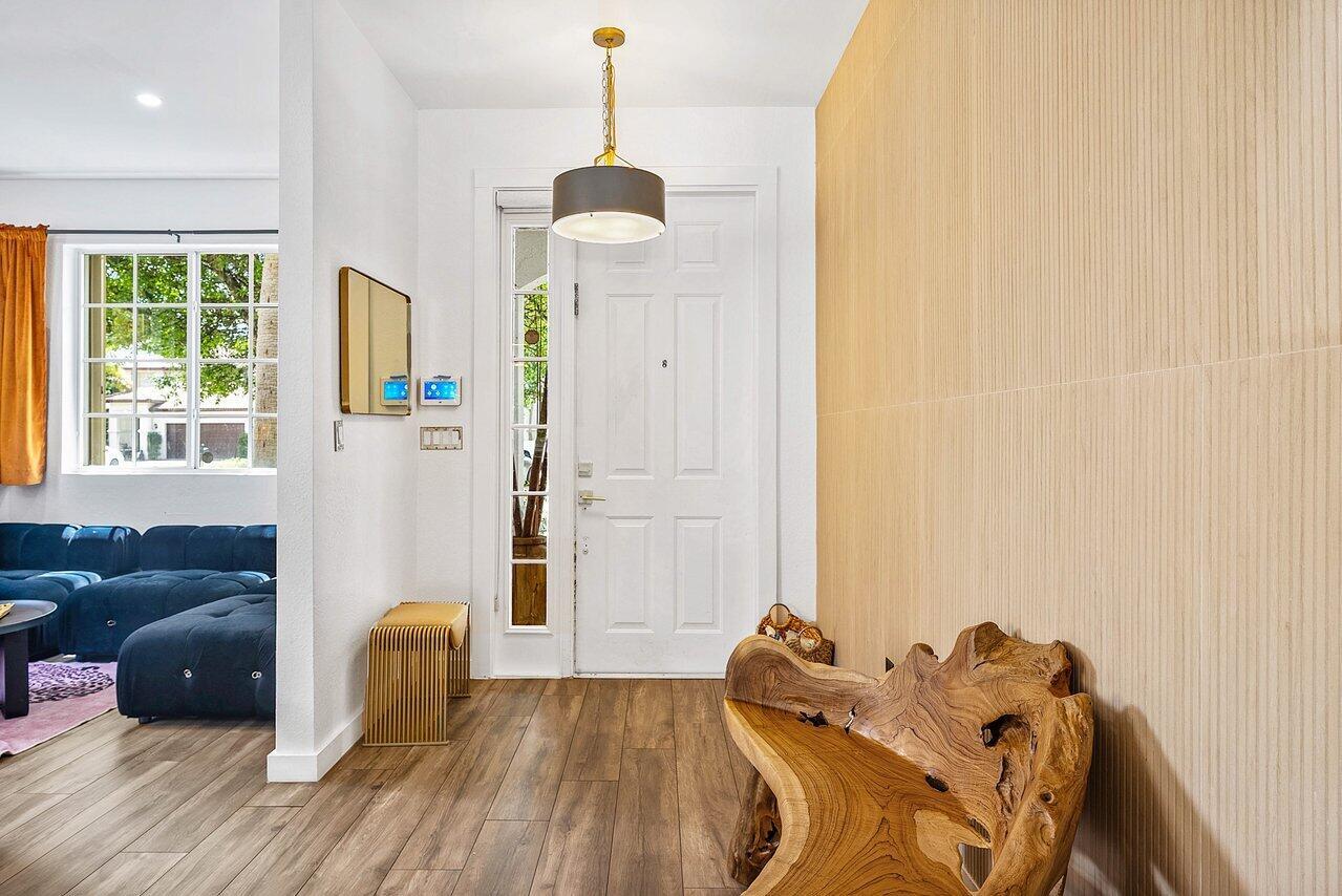 An entryway features a wood-paneled wall, a live-edge wooden bench, and a modern pendant light — 10223 Boca Vista Drive, Boca Raton FL 33498, BOCA RATON, FL