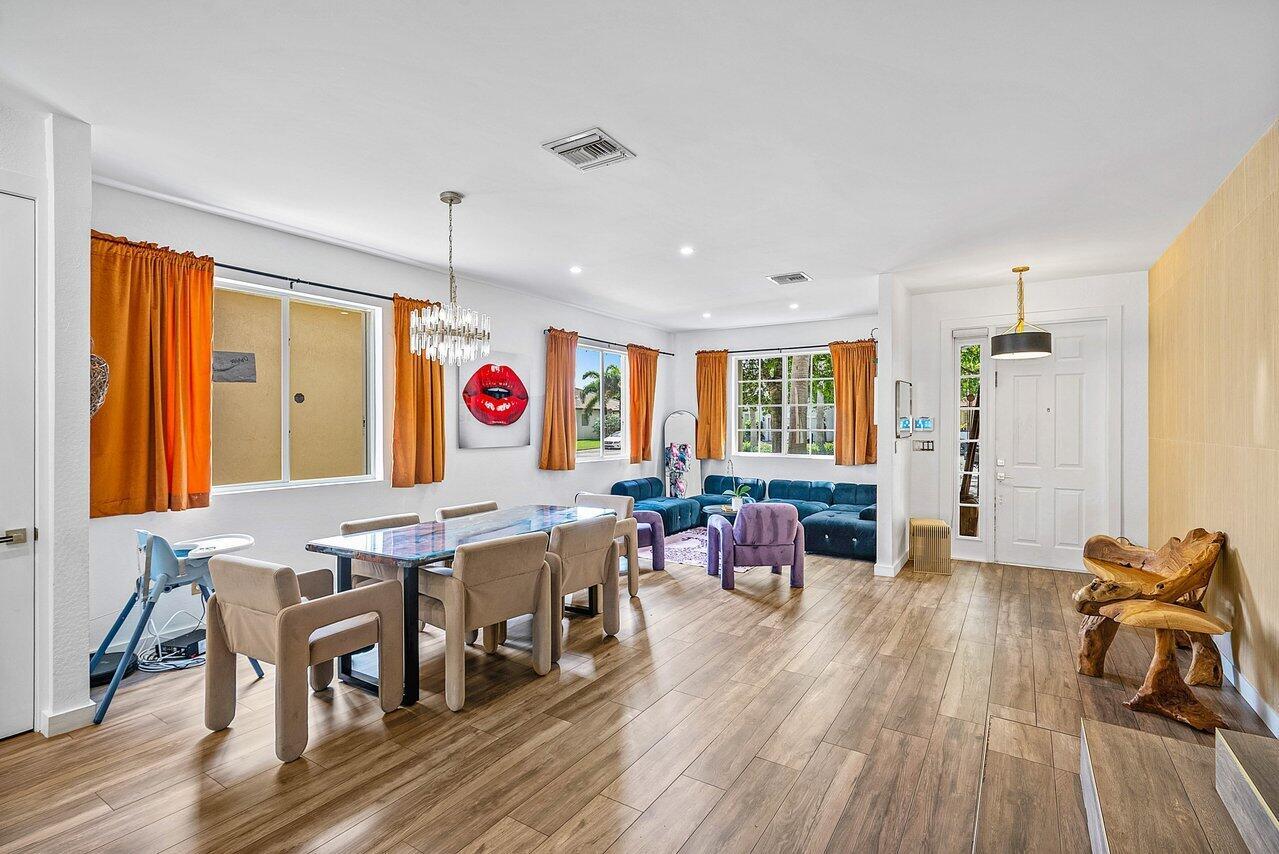 A dining and living area features wood-look flooring, orange curtains, and a blue sectional sofa — 10223 Boca Vista Drive, Boca Raton FL 33498, BOCA RATON, FL