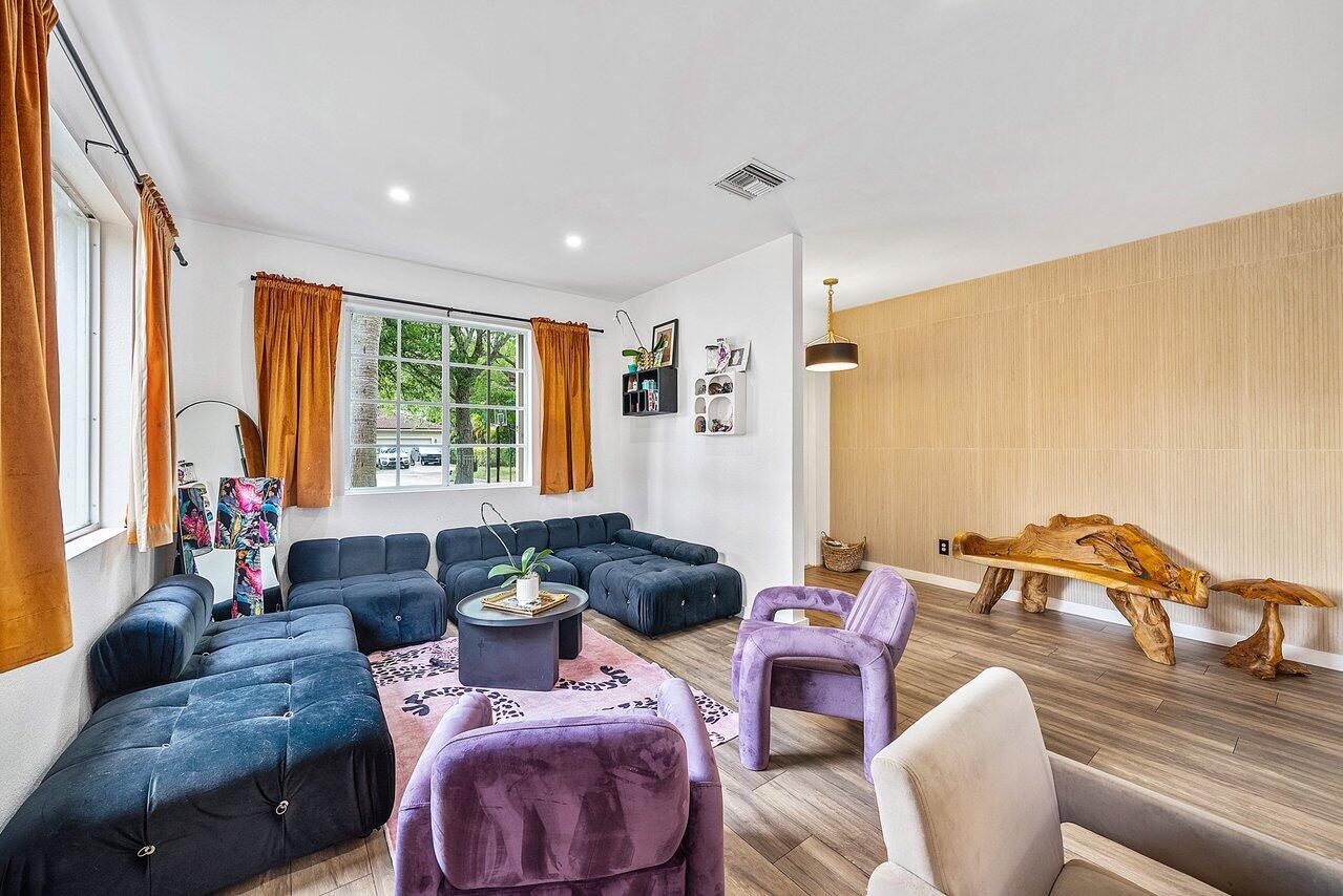 A living room features a dark blue sectional, purple armchairs, and a natural wood bench — 10223 Boca Vista Drive, Boca Raton FL 33498, BOCA RATON, FL