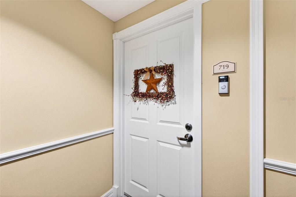 A white door with a decorative wreath and a doorbell camera is labeled number 719 — 4516 SEAGULL DRIVE UNIT 719, NEW PORT RICHEY, FL