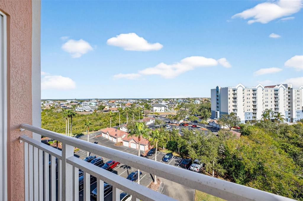 A high-angle view from a balcony overlooking a parking lot, trees, and distant buildings — 4516 SEAGULL DRIVE UNIT 719, NEW PORT RICHEY, FL