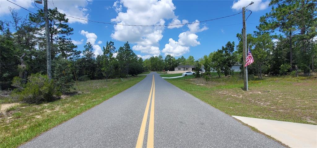 A paved road with double yellow lines leads toward a house surrounded by trees — 10339 N G MARTINELLI BOULEVARD, CITRUS SPRINGS, FL
