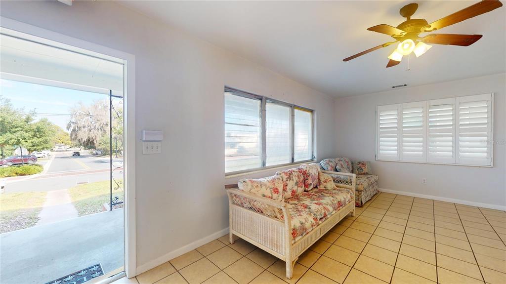 A sunroom features tile flooring, a ceiling fan, and two floral-patterned wicker sofas — 121 N SEMINOLE AVENUE, INVERNESS, FL