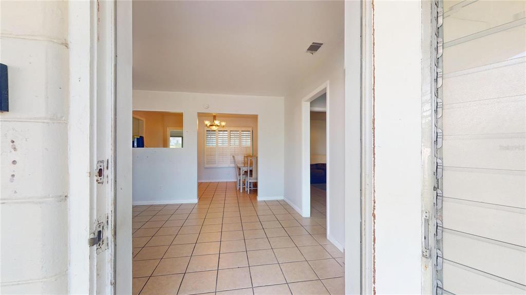 A view through a doorway into a tiled living area with a dining space beyond — 121 N SEMINOLE AVENUE, INVERNESS, FL