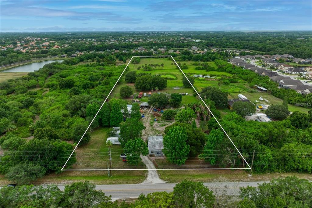 An aerial view shows a large, trapezoidal plot of land with a house and outbuildings — 11920 UPPER MANATEE RIVER ROAD, BRADENTON, FL