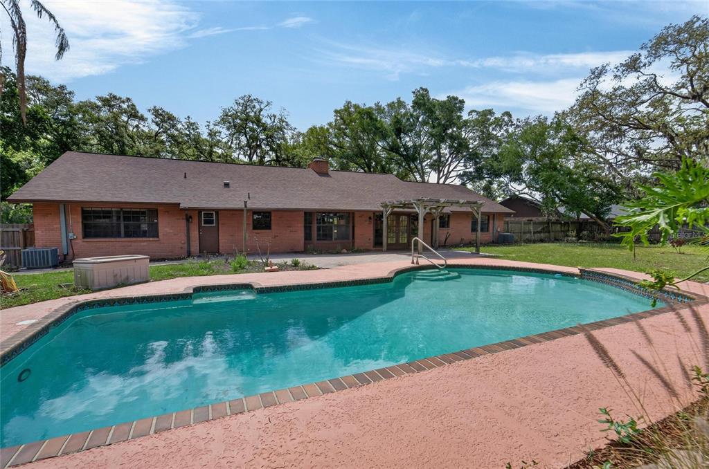 A brick house with a brown roof overlooks a swimming pool and a patio area — 12506 SHADOW RUN BOULEVARD, RIVERVIEW, FL