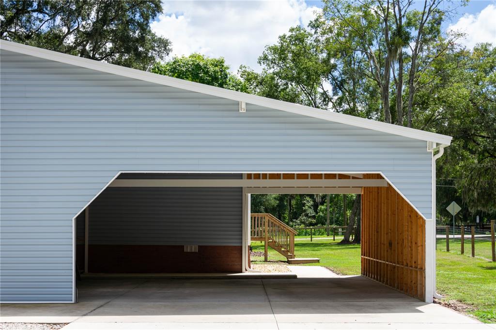 A large, open-sided carport with light blue siding, a concrete floor, and exposed wooden framing — 10015 NW 45TH AVENUE, OCALA, FL