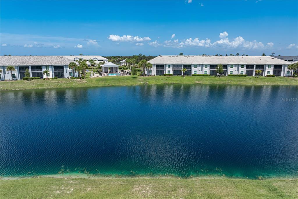A view of a lake bordered by apartment buildings and a small pool structure — 14944 REDBUD LANE, PUNTA GORDA, FL