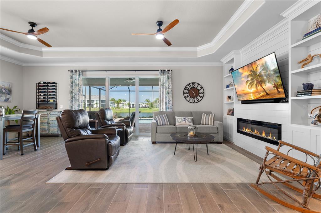 A living room features a fireplace, built-in shelving, a television, and sliding glass doors — 14944 REDBUD LANE, PUNTA GORDA, FL