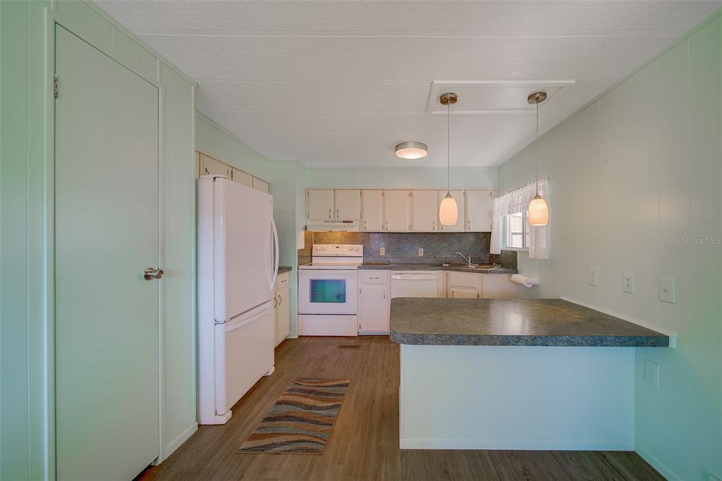 A kitchen with light green walls, white cabinets, white appliances, and a peninsula counter — 12501 ULMERTON ROAD UNIT 128, LARGO, FL