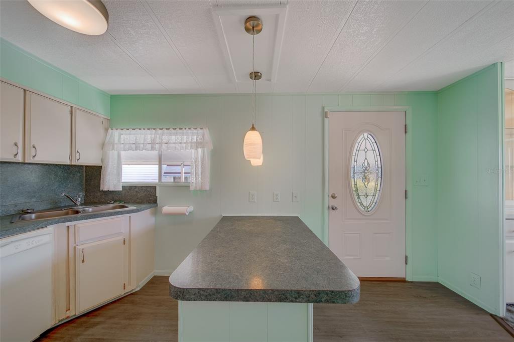 A kitchen with mint green walls, a central island, white cabinets, and a front door — 12501 ULMERTON ROAD UNIT 128, LARGO, FL
