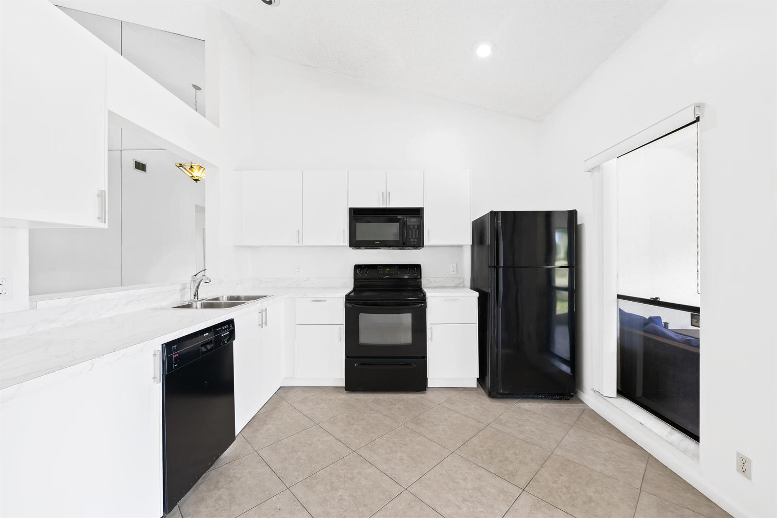 A kitchen with white cabinets, marble-look countertops, black appliances, and light-colored tile flooring — 9260 Ketay Circle, Boca Raton FL 33428, BOCA RATON, FL