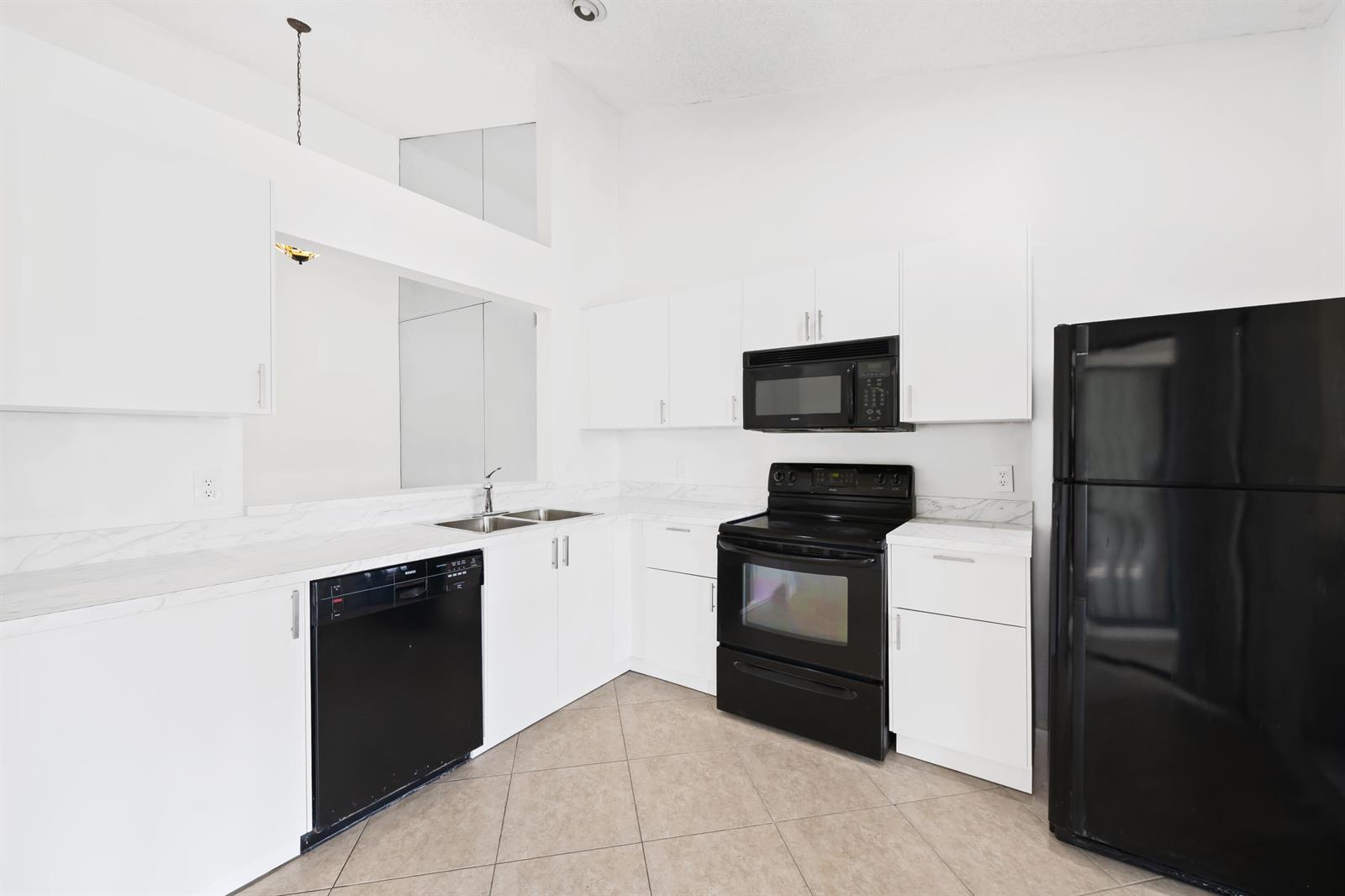 A kitchen features white cabinets, black appliances, and a marble-patterned countertop on tiled flooring — 9260 Ketay Circle, Boca Raton FL 33428, BOCA RATON, FL