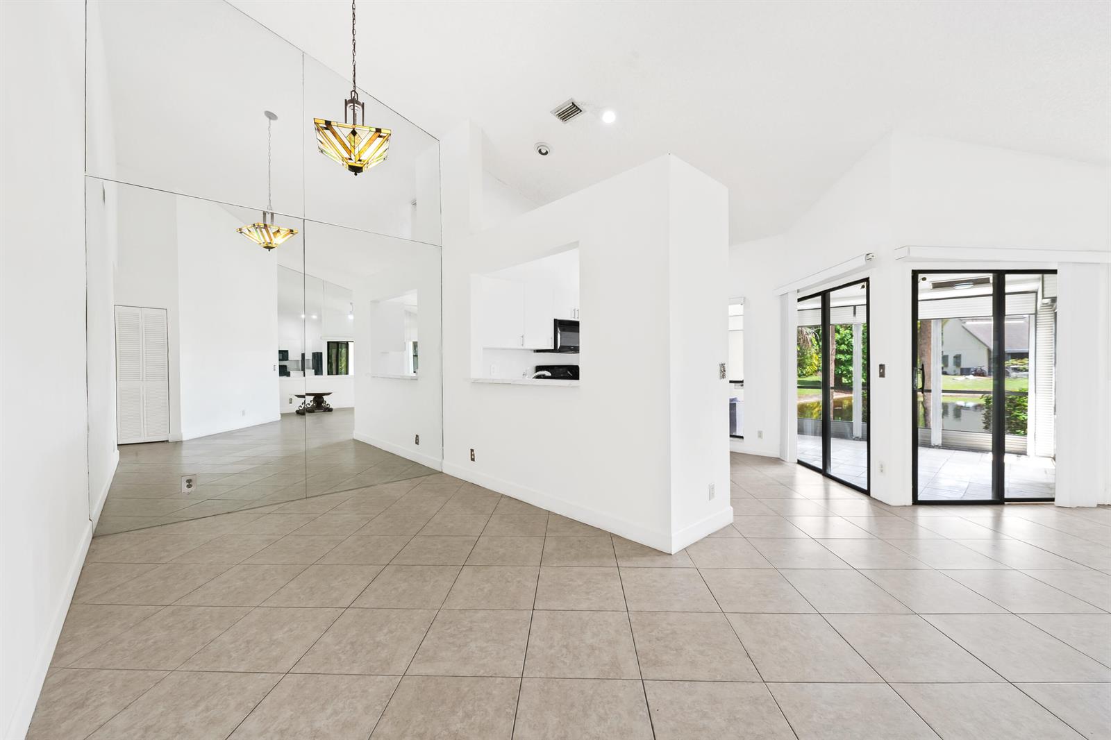 A bright living area features tiled floors, a mirrored wall, and a kitchen pass-through window — 9260 Ketay Circle, Boca Raton FL 33428, BOCA RATON, FL