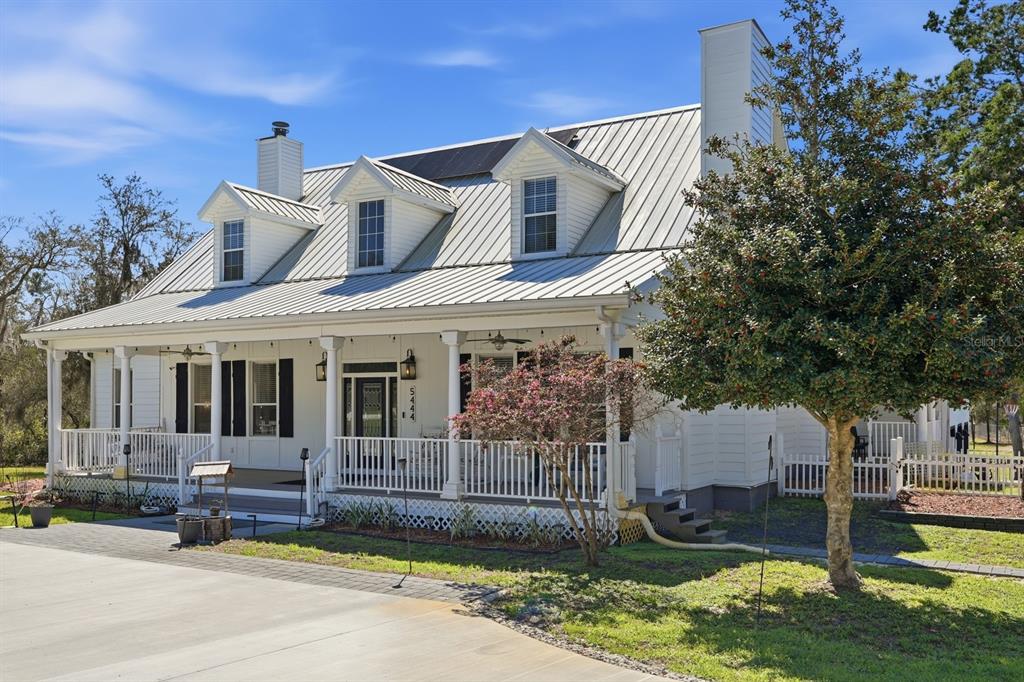 A white two-story house with a metal roof and a large wrap-around front porch — 5444 US HIGHWAY 17, DE LEON SPRINGS, FL