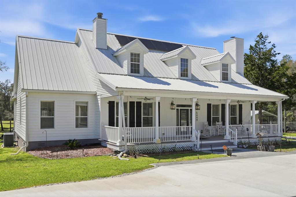 A white two-story farmhouse with a metal roof, front porch, and dormer windows — 5444 US HIGHWAY 17, DE LEON SPRINGS, FL