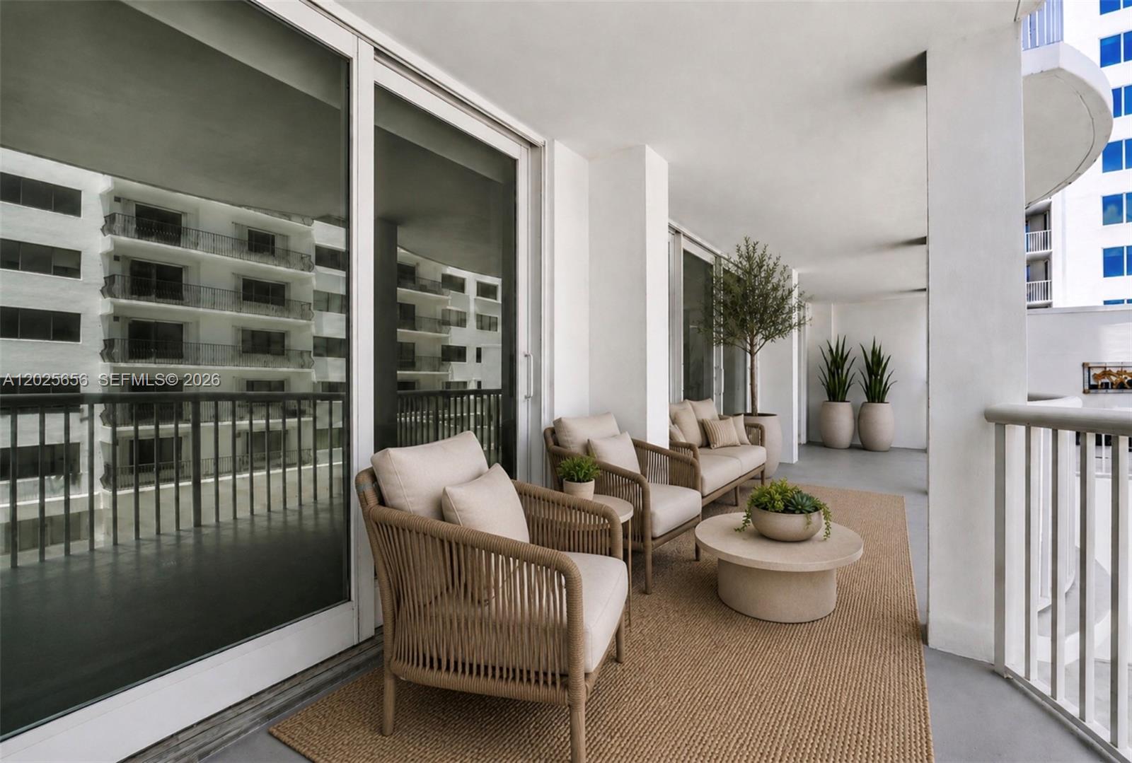A balcony features outdoor furniture, a rug, potted plants, and sliding glass doors — 5401 Collins Ave # 107, Miami Beach FL 33140, MIAMI BEACH, FL
