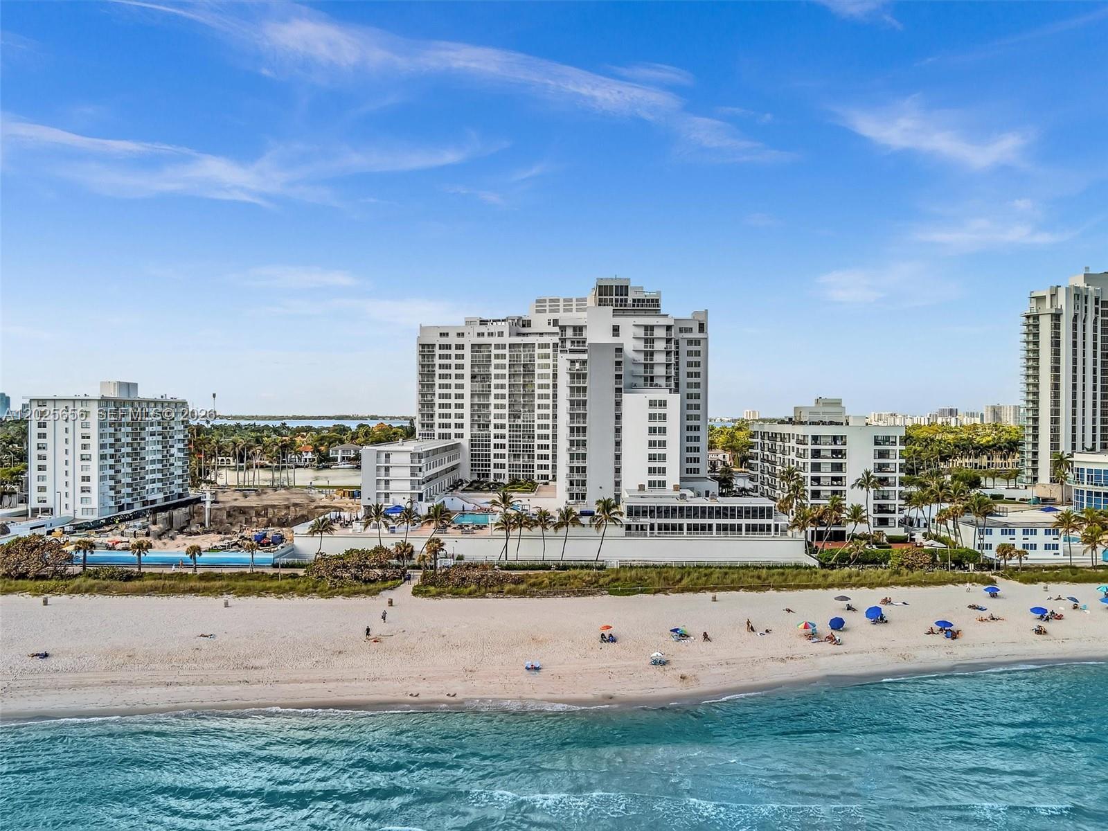 An aerial view shows several high-rise apartment buildings situated directly behind a sandy beach — 5401 Collins Ave # 107, Miami Beach FL 33140, MIAMI BEACH, FL