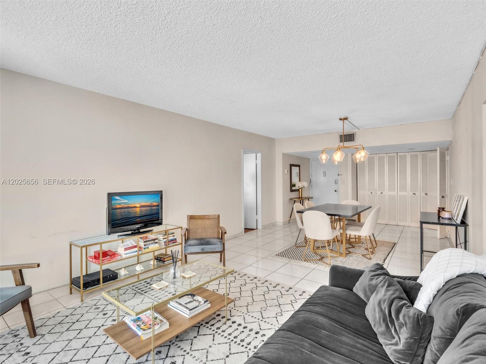 A living and dining area features white tile floors, a grey sofa, and a glass-topped table — 5401 Collins Ave # 107, Miami Beach FL 33140, MIAMI BEACH, FL