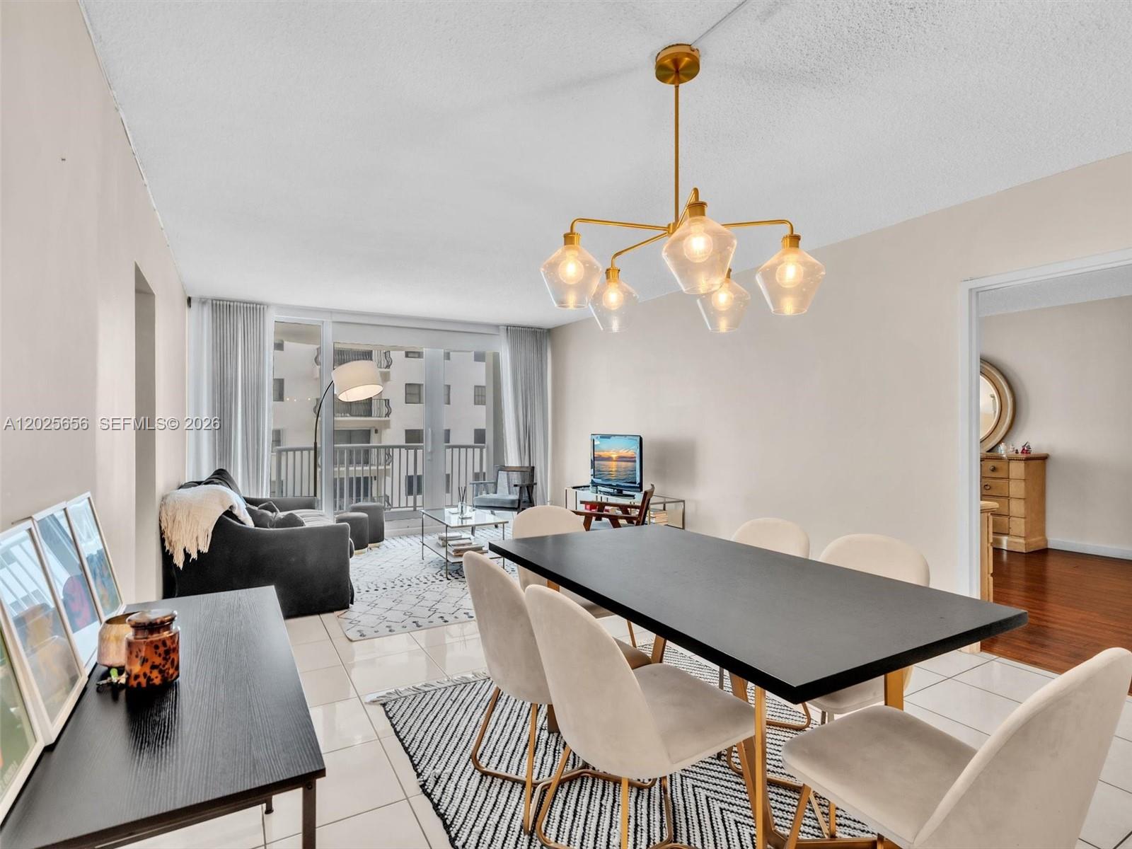 A dining area with a black table and chairs sits adjacent to a living room — 5401 Collins Ave # 107, Miami Beach FL 33140, MIAMI BEACH, FL