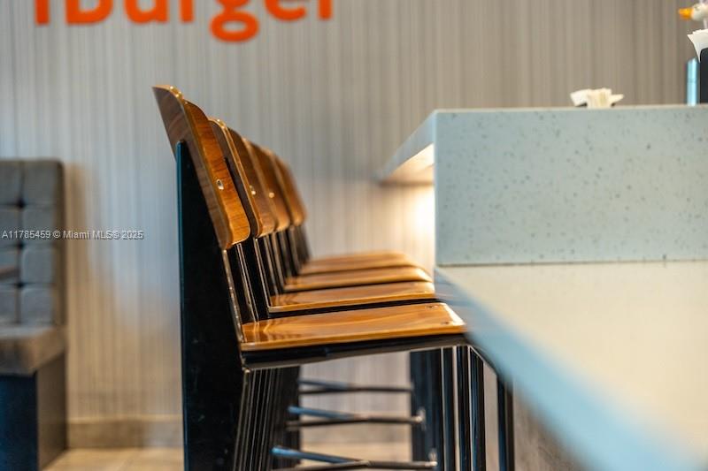 A row of wooden bar stools sits along a light-colored counter in a restaurant — 275 NE 18th St # CU-2, Miami FL 33132, MIAMI, FL
