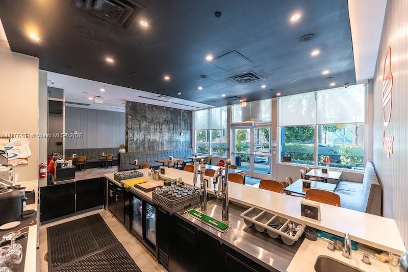 A modern restaurant interior features a stainless steel service counter, dark ceiling, and booth seating — 275 NE 18th St # CU-2, Miami FL 33132, MIAMI, FL