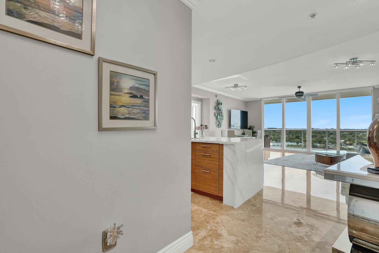 A view from a hallway into a modern kitchen and living area with marble floors — 1 N Ocean Boulevard # 814, Pompano Beach FL 33062, POMPANO BEACH, FL