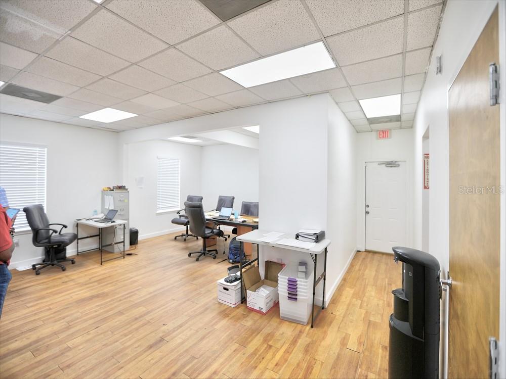 An office space features white walls, drop ceilings, wood-look flooring, and several desks with chairs — 631 E OAK RIDGE ROAD, ORLANDO, FL