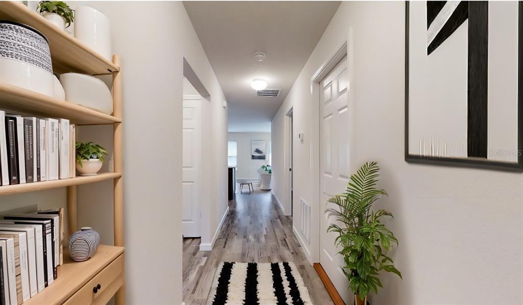 A hallway with light wood flooring, a bookshelf on the left, and a white door — 26 RIDDLE DRIVE, PALM COAST, FL