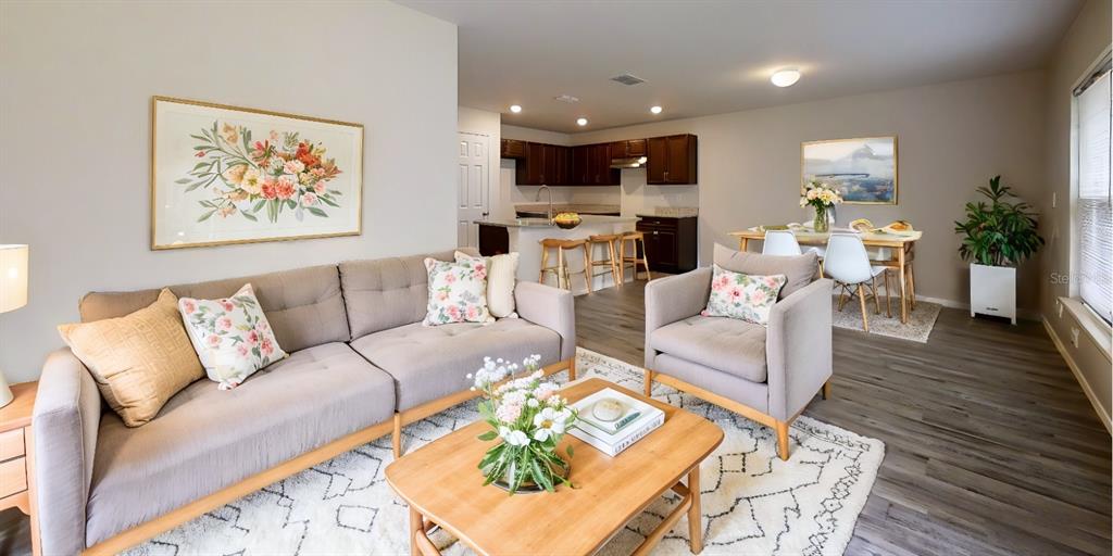 A living room with a sofa and armchair opens to a kitchen and dining area — 26 RIDDLE DRIVE, PALM COAST, FL