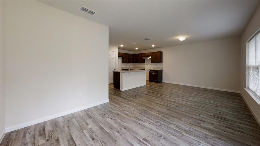 An open-concept kitchen with dark cabinets and a center island overlooks a spacious living area — 26 RIDDLE DRIVE, PALM COAST, FL