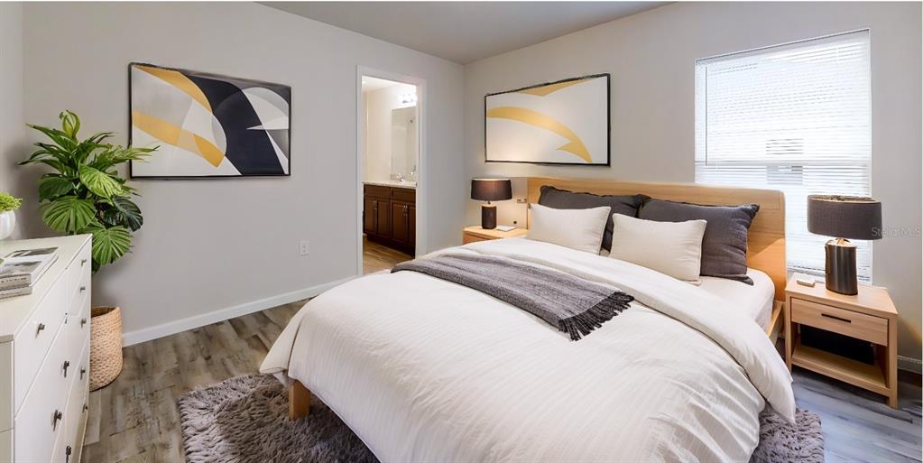 A bedroom features a bed with white bedding, two nightstands, wall art, and wood flooring — 26 RIDDLE DRIVE, PALM COAST, FL