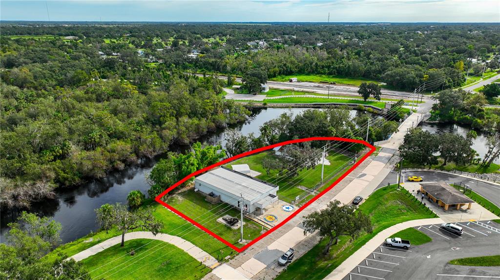 An aerial view shows a commercial building on a waterfront lot near a parking area — 2124 NW AMERICAN LEGION DRIVE, ARCADIA, FL