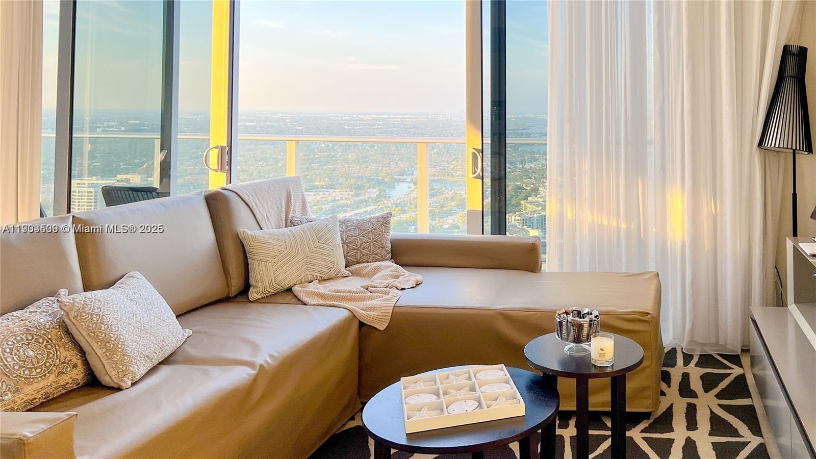 A living room features a tan sectional sofa, two small round tables, and floor-to-ceiling windows — 4010 S Ocean Dr # T4302, Hollywood FL 33019, HOLLYWOOD, FL