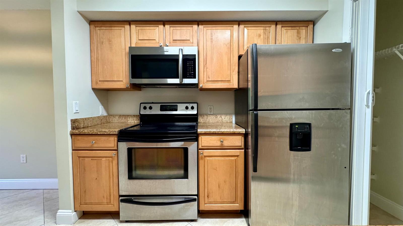A kitchen features light wood cabinets, stainless steel appliances, and granite countertops — 815 W Boynton Beach Boulevard # 105, Boynton Beach FL 33426, BOYNTON BEACH, FL